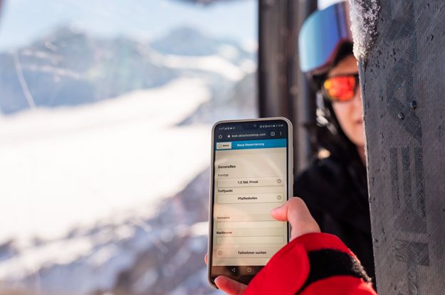 Skilehrerin nutzt die Skilehrer-App in der Gondel